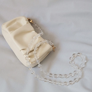 Detail of a creamy white pleated cloud clutch bag with transparent acrylic bead shoulder strap
