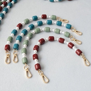 Close-up of colorful acrylic beaded straps with white pearls and gold metal lobster clasps