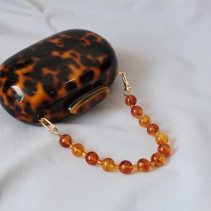 Detail of tortoiseshell acrylic handbag with amber beaded handle and gold metal clips