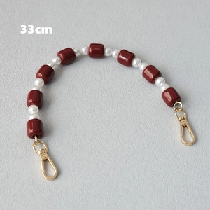 Detail of 33cm acrylic chain featuring dark red beads, pearls and gold lobster clasps