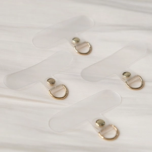Universal clear PVC phone tether tabs with gold D-rings on white silk background