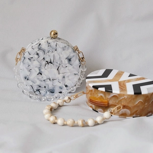 Detail of acrylic dinner clutch bag with marble pattern texture and beaded handle