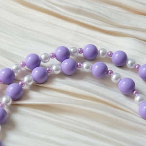 Vue détaillée de perles acryliques violettes et perles blanches sur satin doux