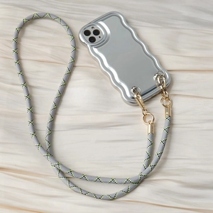 Detail of silver wavy phone case with grey and yellow woven crossbody strap on silk