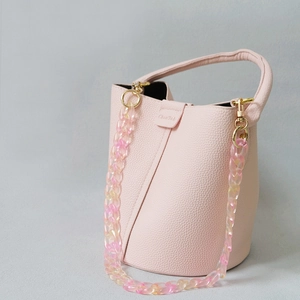 Détail du sac seau en cuir rose avec chaîne décorative en résine acrylique dégradée