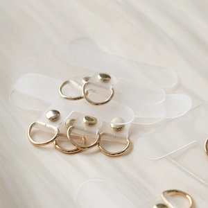 Close-up of frosted TPU phone lanyard patches with gold alloy rings on white silk fabric