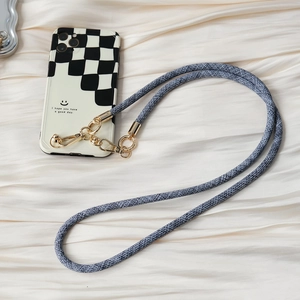 Detail of checkered phone case with cross-body woven strap and gold metal hardware