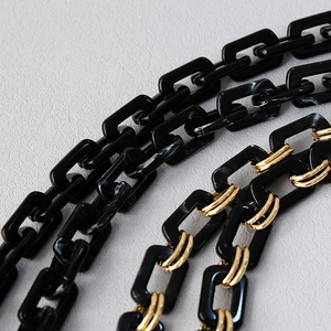 Detail of black acrylic resin chain links with gold metal connectors for handbags