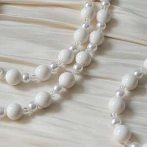 Détail de perles en acrylique blanc et perles nacrées sur un fond de soie douce