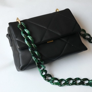 Quilted black leather crossbody bag featuring a thick green acrylic marble chain strap