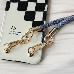 Detail of checkered phone case with smiley face and blue braided lanyard with gold hooks