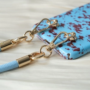 Detail of light blue braided phone lanyard with gold metal clips and marble case