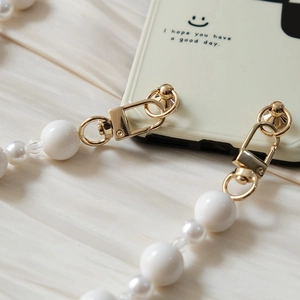 Détail de la dragonne de téléphone en perles blanches avec fermoir doré sur soie