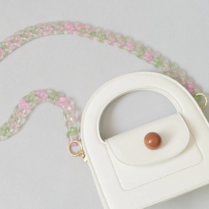 Gros plan d'un mini sac à main blanc avec chaîne en résine rose et verte et perle décor