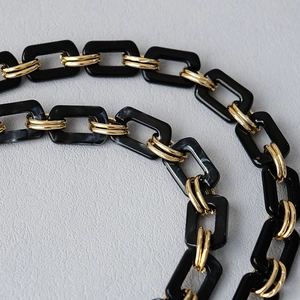 Macro shot of stylish black marble resin links and gold metal rings for handbag straps