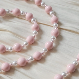 Détail de perles acryliques colorées sur fond de satin crème pour sangles de mode