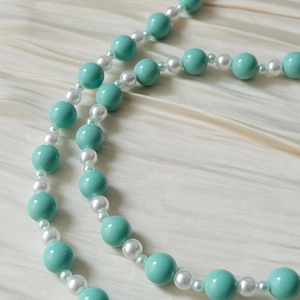 Détail de perles en acrylique bleu tiffany et perles blanc crème sur du satin plissé doux
