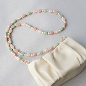 Detail of white cloud pleated handbag with mint and pink acrylic bead strap