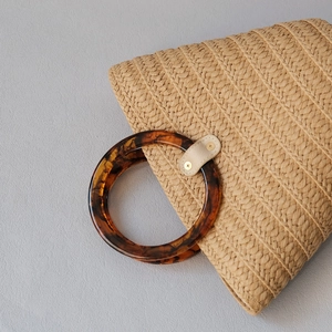 Handcrafted straw tote bag featuring vintage amber resin handles and secure leather patches