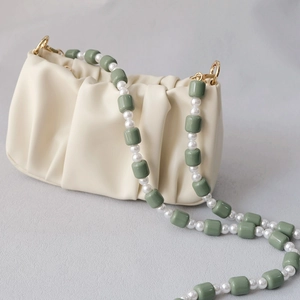 Detail of candy-colored resin beads and faux pearls on a beige pleated cloud bag strap
