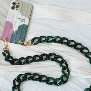Detail view of dark green acrylic chain strap on wavy patterned pastel phone case