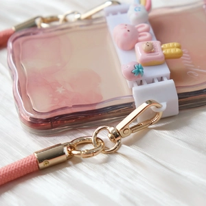 Detail of pink wavy phone case with cute 3D charms and braided crossbody strap