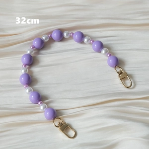 Détail d'une bandoulière de 32cm en perles acryliques avec fermoirs en métal doré