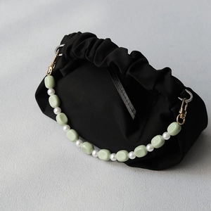 Detail of black pleated fabric bag with green and white acrylic bead handle and gold hardware