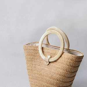 Close-up of a 11.8cm marble-patterned resin handle on a handcrafted woven straw bag
