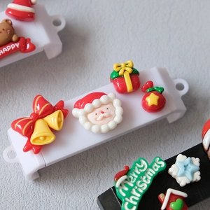 Macro shot of 3D resin Christmas charms featuring Santa and gingerbread house details