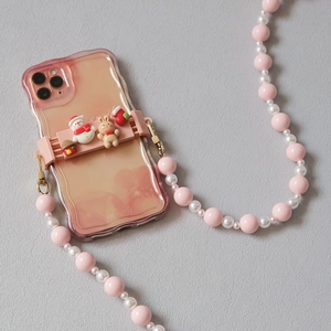 Pink wavy iPhone case with Christmas cartoon grip and pearl strap on grey surface