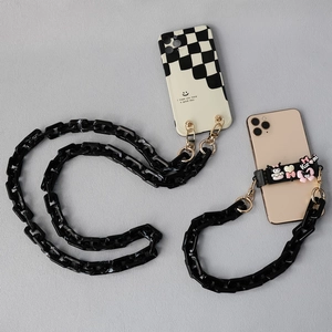 Detail of chunky black marble acrylic chain strap with gold metal buckles and charms