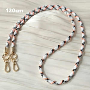 Detail of 120cm black, white, and orange braided crossbody phone strap with gold metal clasps