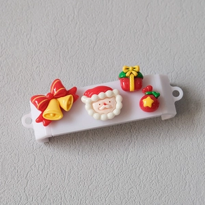 Detail view of 4 Christmas resin charms like Santa and bells on a white phone grip base