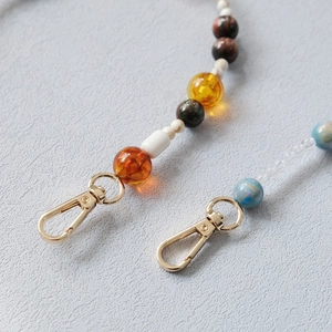 Detail of colorful acrylic beads and resin stones with golden metal lobster clasps