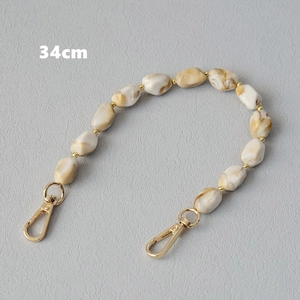 Dettaglio della catena da 34cm in resina marmorizzata beige con chiusure a moschettone oro