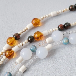 Macro detail of acrylic bead chain with amber, emerald, and white resin beads for necklaces
