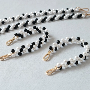 Dettaglio tracolla intrecciata in perle bianche e nere con chiusure dorate per borse moda