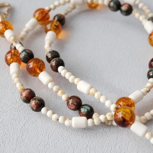 Macro detail of acrylic bead chain with amber resin beads and golden lobster clasp