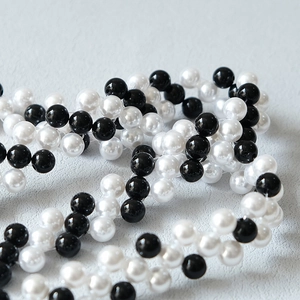 Dettaglio della catena per borsa con perle intrecciate in bianco e nero chic