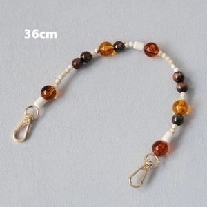 Detail view of 36cm acrylic bead chain with golden lobster clasps in amber and cream tones
