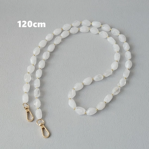 Dettaglio della tracolla di 120cm in perle acriliche bianche con moschettoni dorati