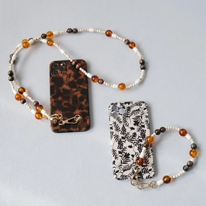 Detail of beaded phone straps with leopard and floral cases featuring golden lobster clasps