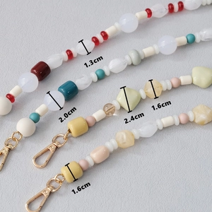 Close-up of acrylic bead chains showing diameters from 1.3cm to 2.4cm with gold lobster clasps