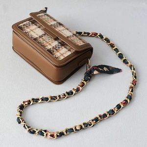 Detail view of the brown plaid crossbody bag with silk scarf interwoven gold chain strap