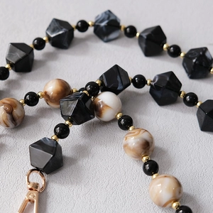 Macro detail of acrylic bead strap with marble pattern beads and gold metal connectors