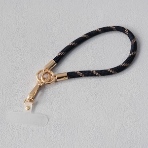 Détail de la lanière de téléphone tressée noir et or avec anneau en métal et connecteur