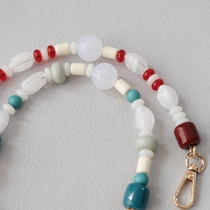 Detail of colorful acrylic bead strap with smooth resin textures and gold lobster clasp