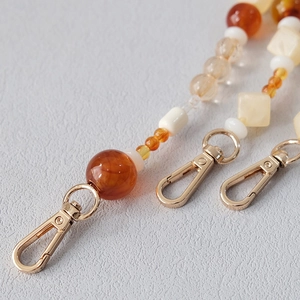 Detailed macro view of amber and cream resin beaded chain with golden lobster clasp