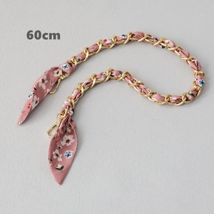 Détail d'une bandoulière de 60cm en soie rose fleurie entrelacée d'une chaîne dorée
